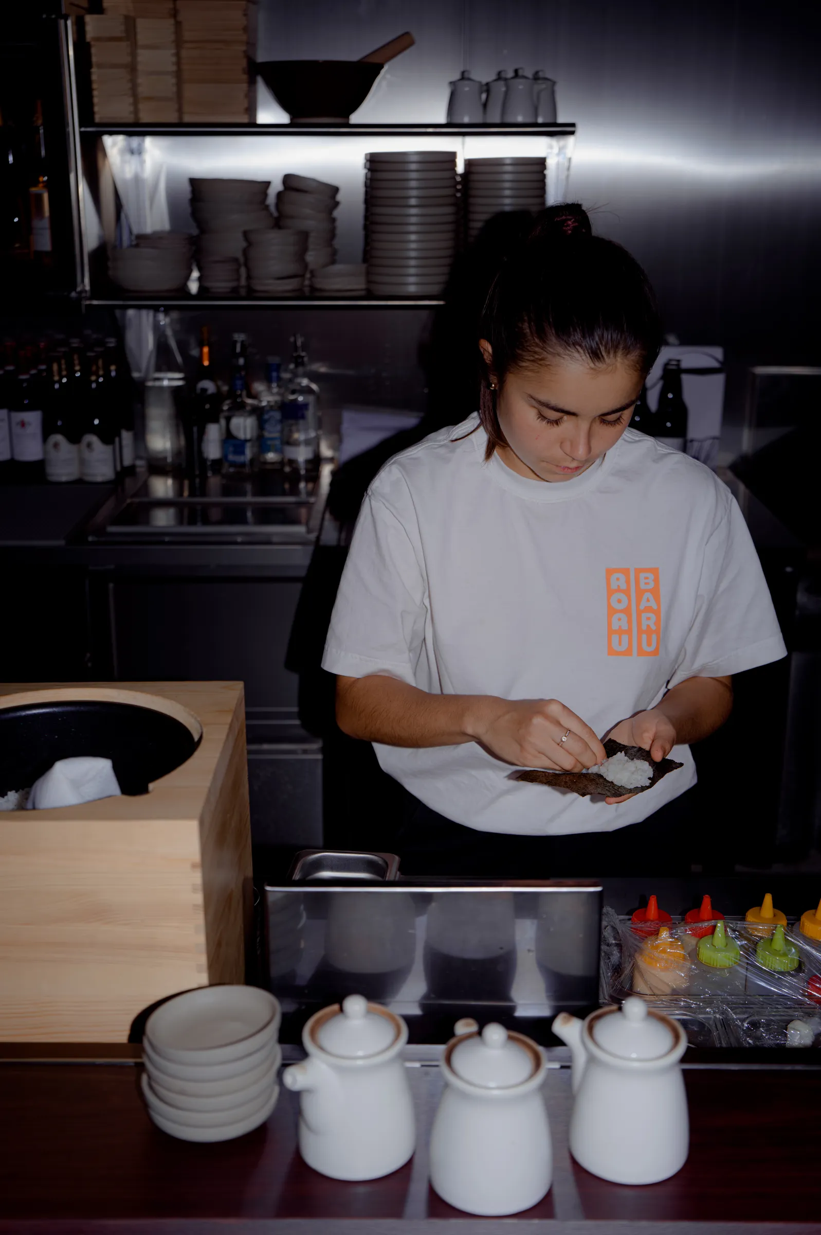 A RORUBARU chef hand-rolling temaki with rice and Japanese nori at the counter